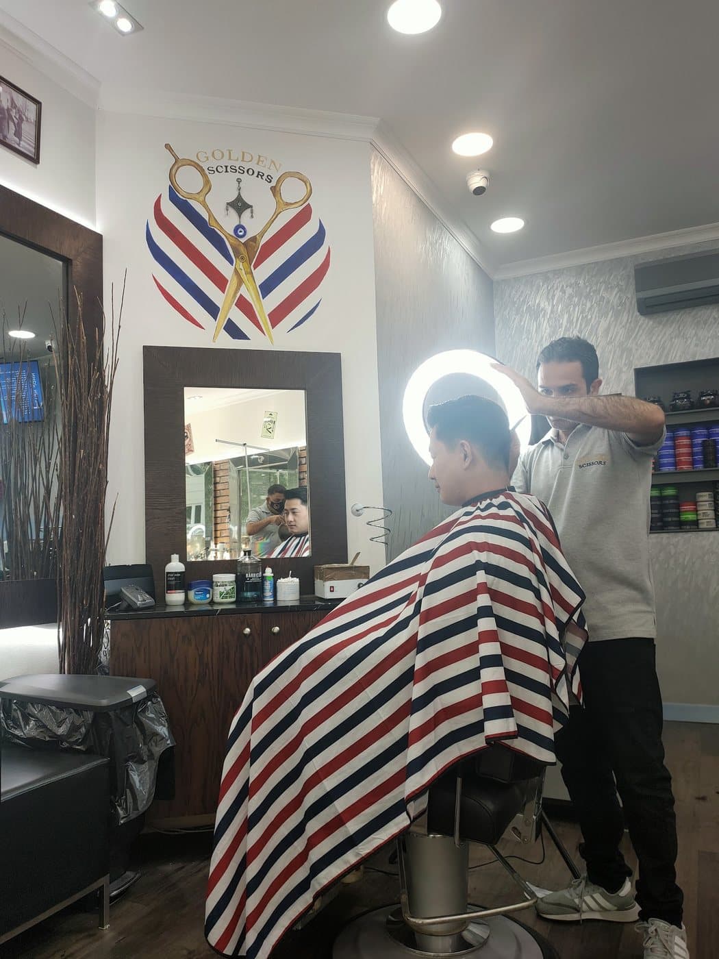 A barber finishing a cut under the ring light